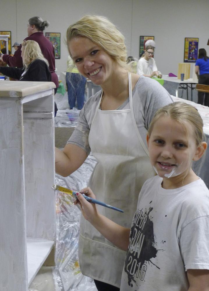 Brandy Wollen painting a piece of furniture with a youth