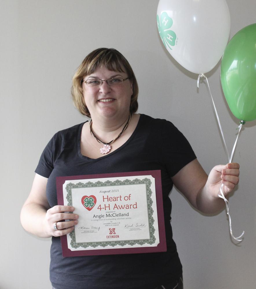 Angie McClelland holding 4-H balloons and a certificate.