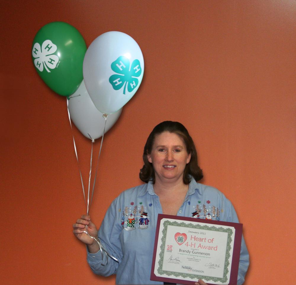 Brandy Gunnerson holding 4-H balloons and a certificate