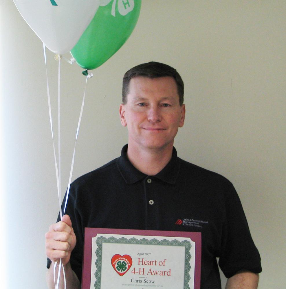 Chris Scow holding balloons and a certificate