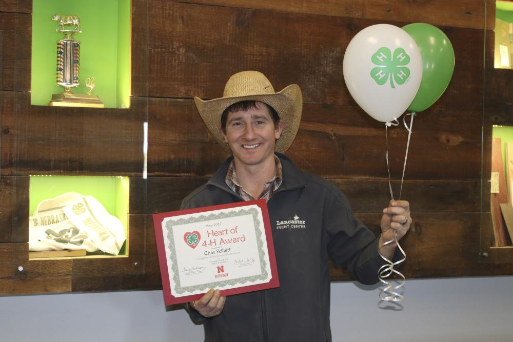 Chas Skillet holding 4-H balloons and a certificate