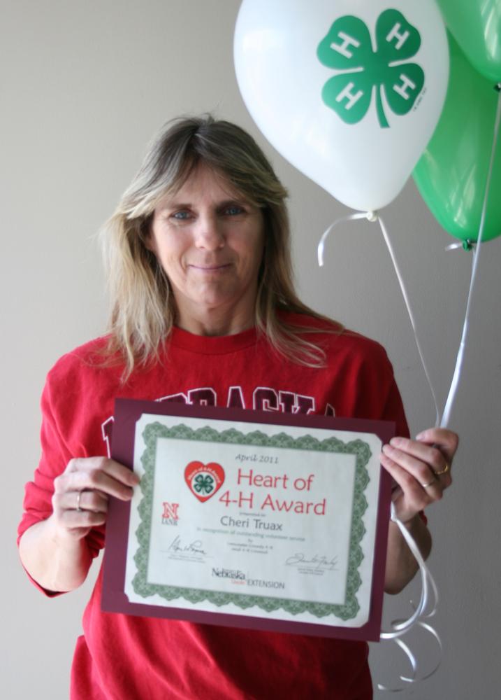 Cheri Truax holding 4-H balloons and a certificate.