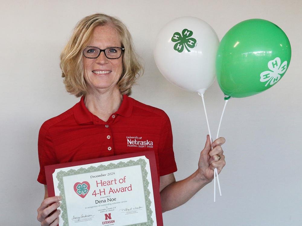 Dena Noe holding a certificate and balloons.