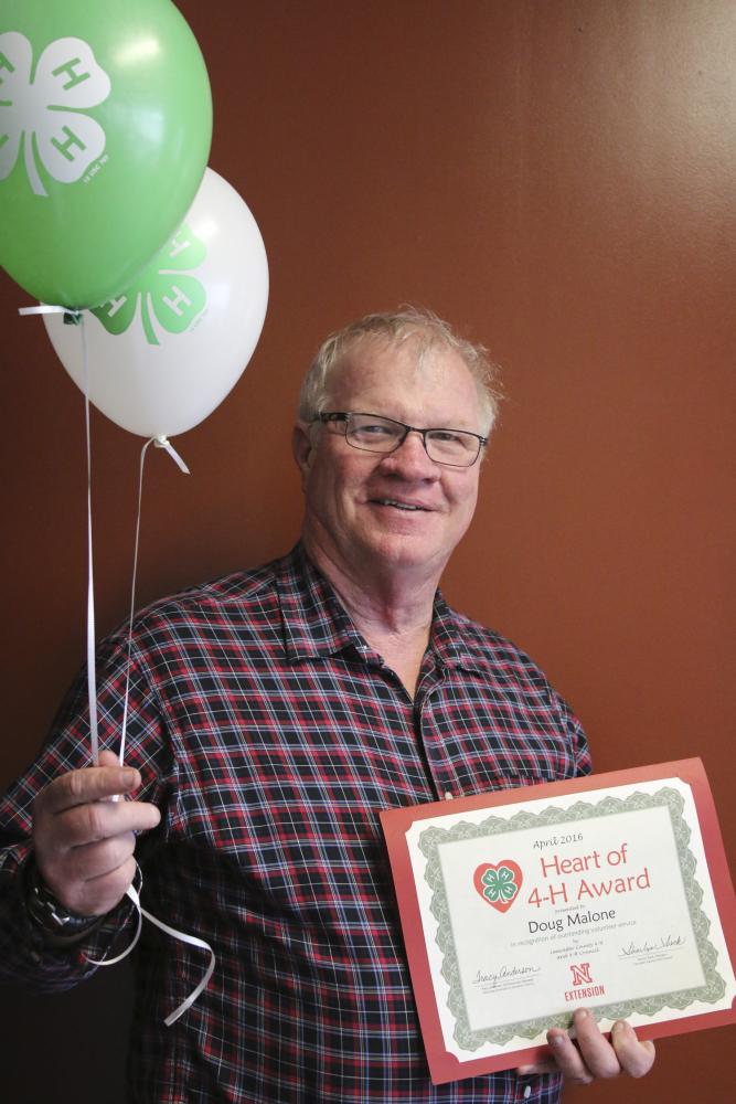 Doug Malone holding 4-H balloons and a certificate.