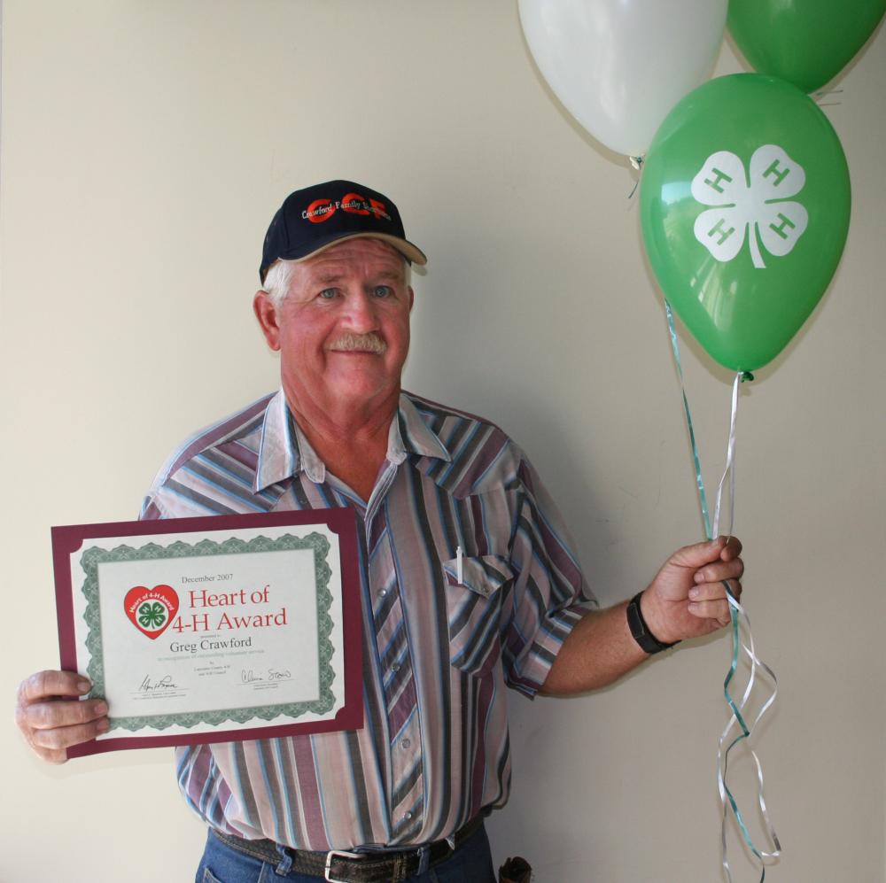 Greg Crawford holding balloons and a certificate