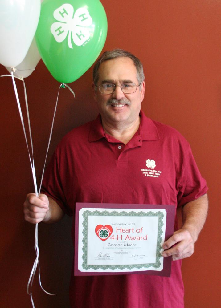 Gordon Maahs holding 4-H balloons and a certificate