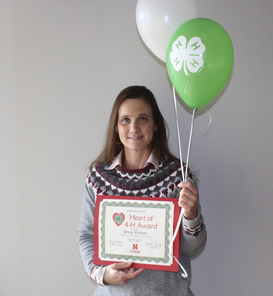Jenny Schnase holding 4-H balloons and a certificate.