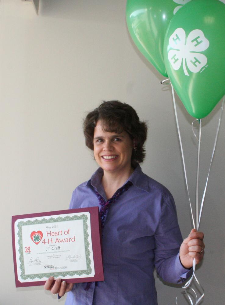 Jill Greff holding 4-H balloons and a certificate.