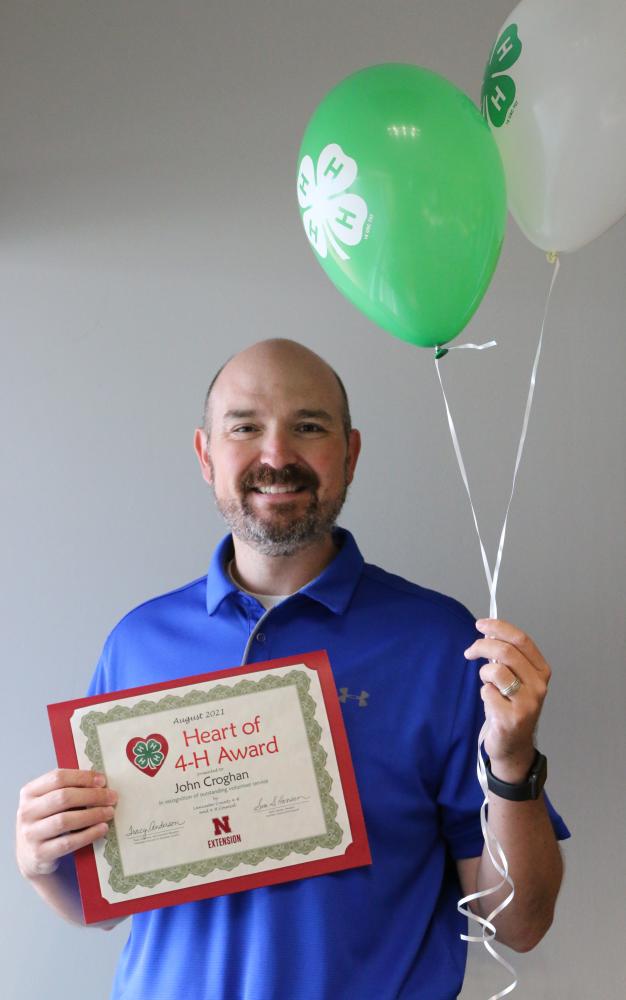 John Croghan holding 4-H balloons and a certificate.