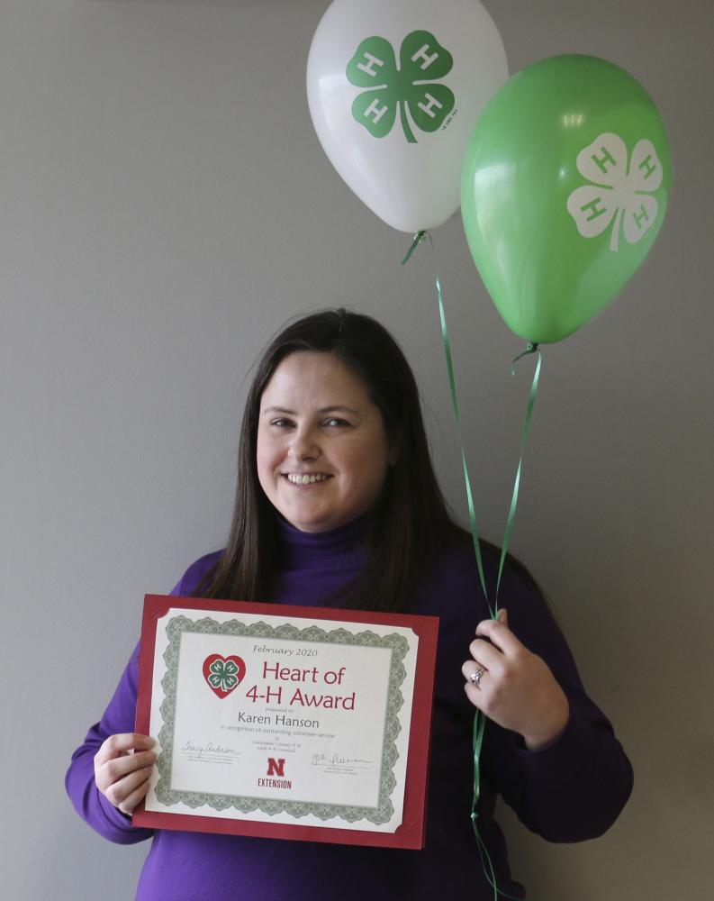 Karen Hanson holding 4-H balloons and a certificate.