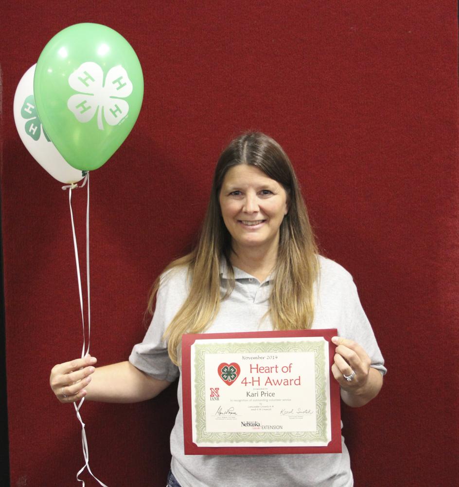 Kari Price holding 4-H balloons and a certificate.