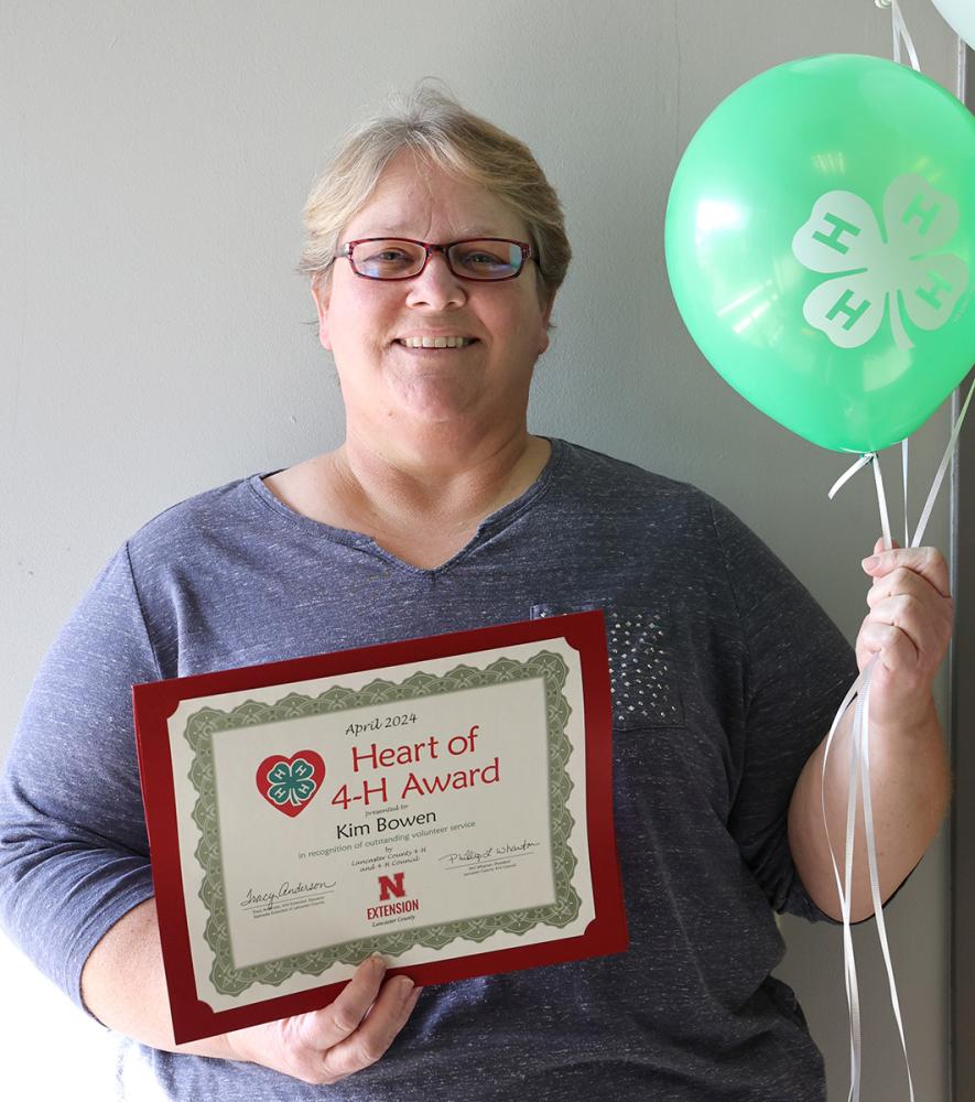 Kim Bowen holding a green balloon with certificate.