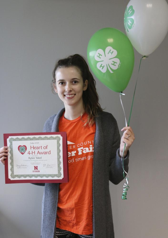 Kylee Yakel holding 4-H balloons, and a certificate.