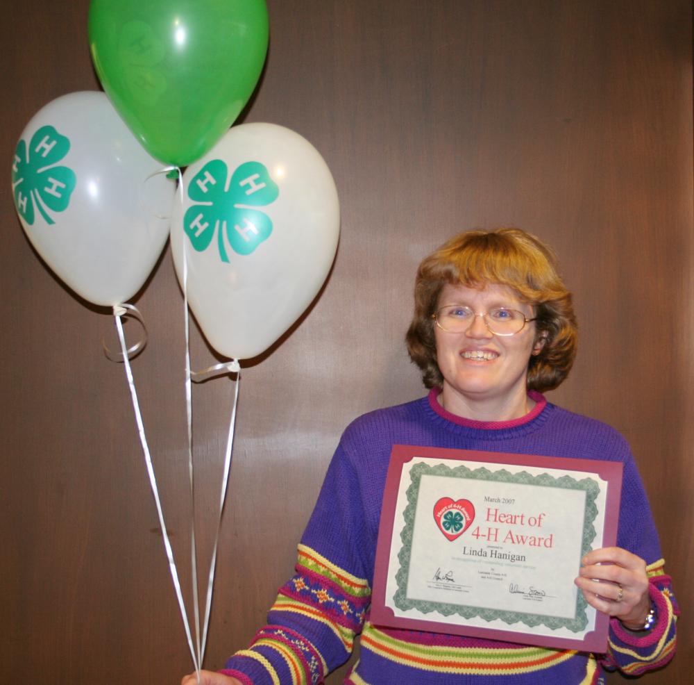 Linda Hanigan holding balloons and a certificate