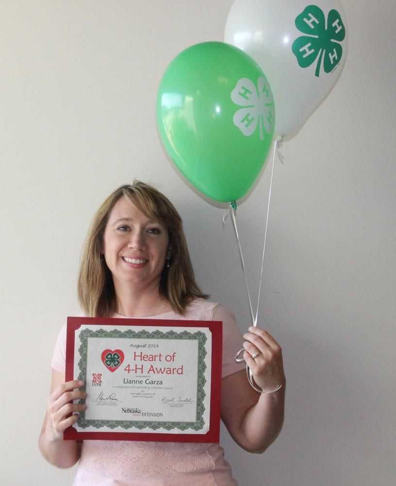 Lianne Garza holding 4-H balloons and a certificate.