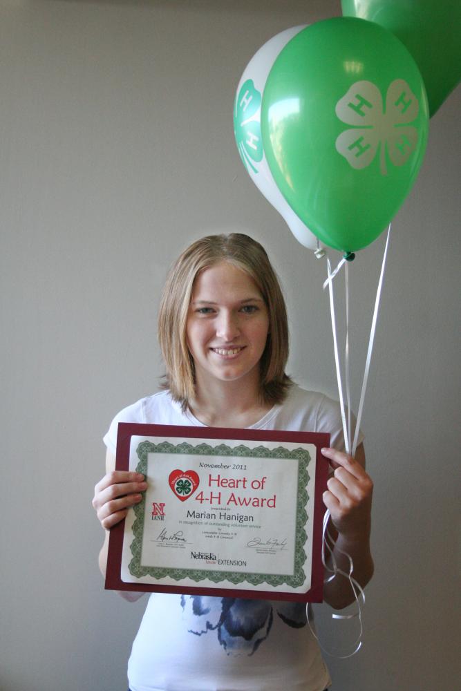 Marian Hanigan holding 4-H balloons and a certificate.
