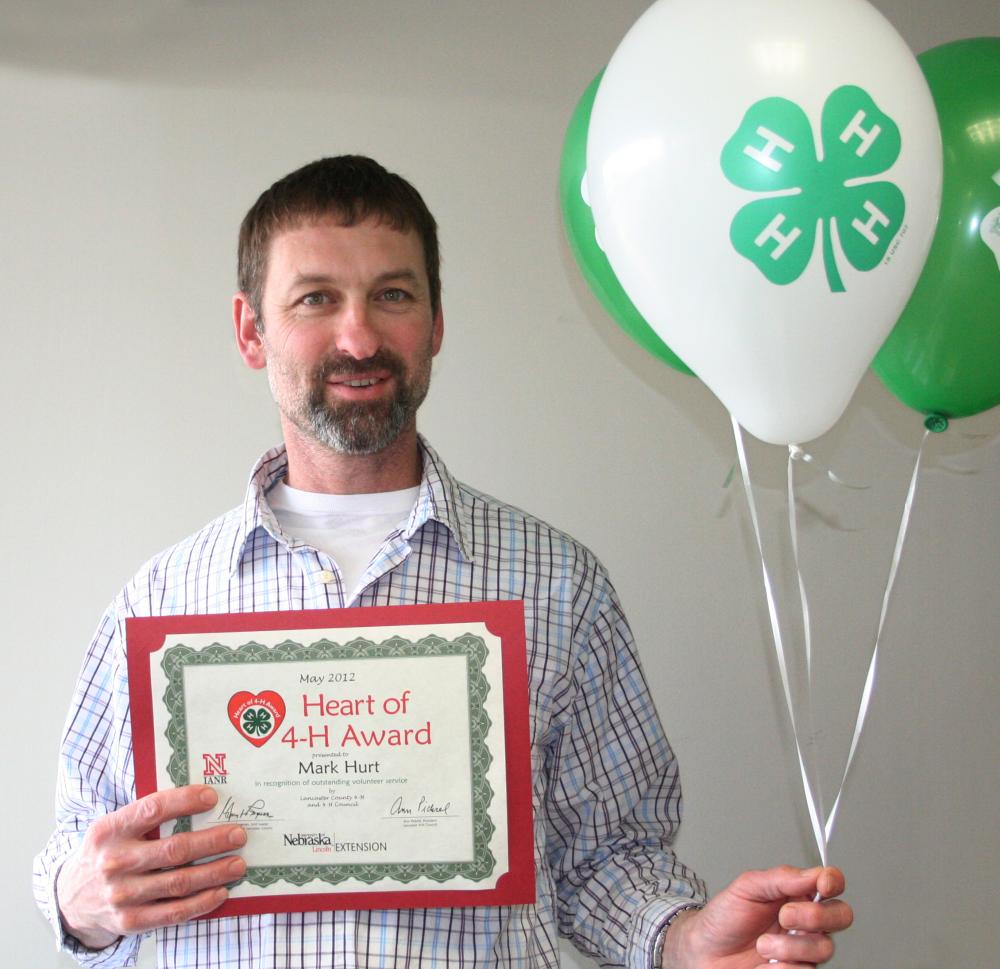 Mark Hurt holding 4-H balloons and a certificate.
