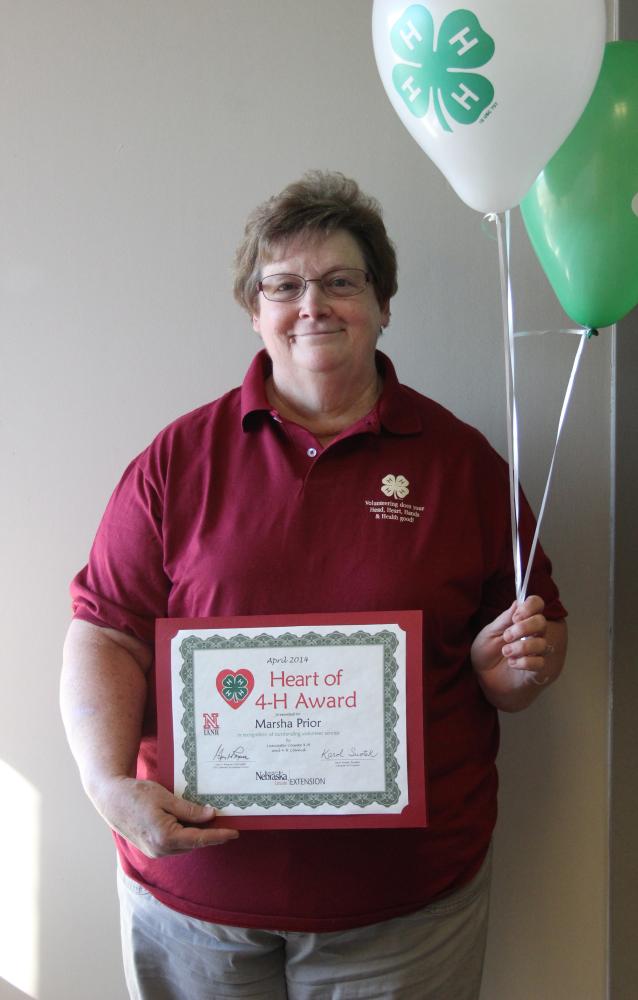 Marsha Prior holding 4-H balloons and a certificate.