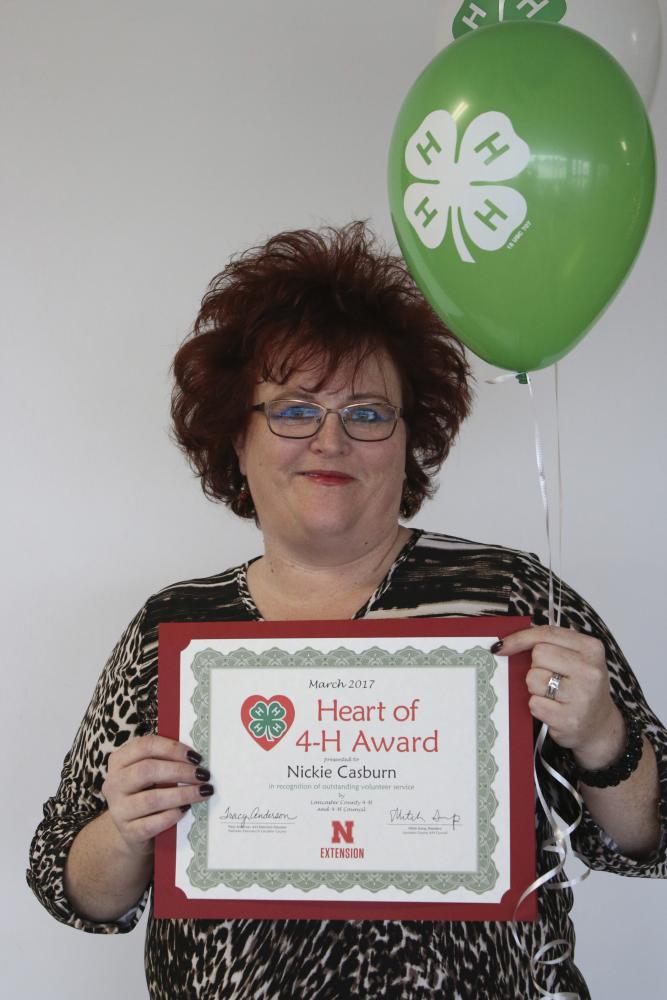 Nickie Casburn holding 4-H balloons and a certificate.