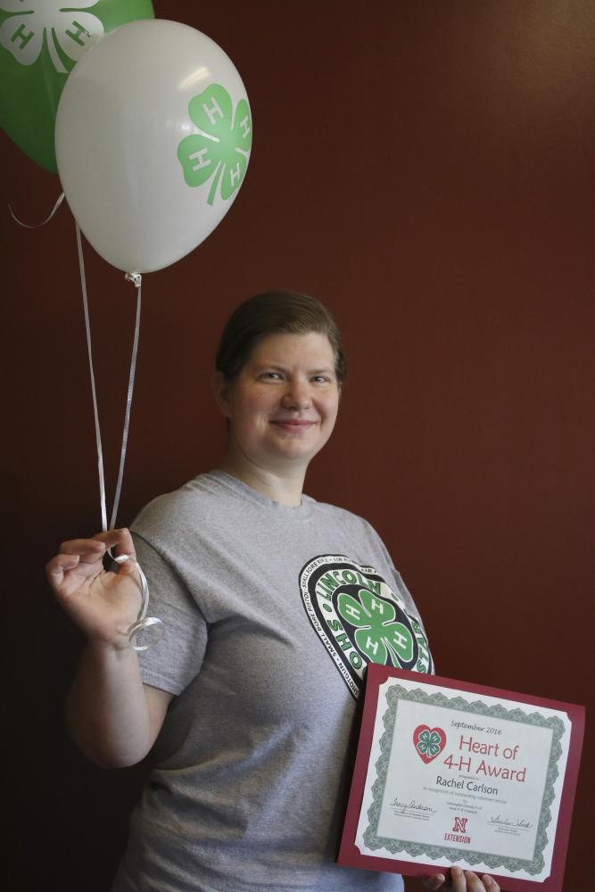 Rachel Carlson holding 4-H balloons and a certificate.
