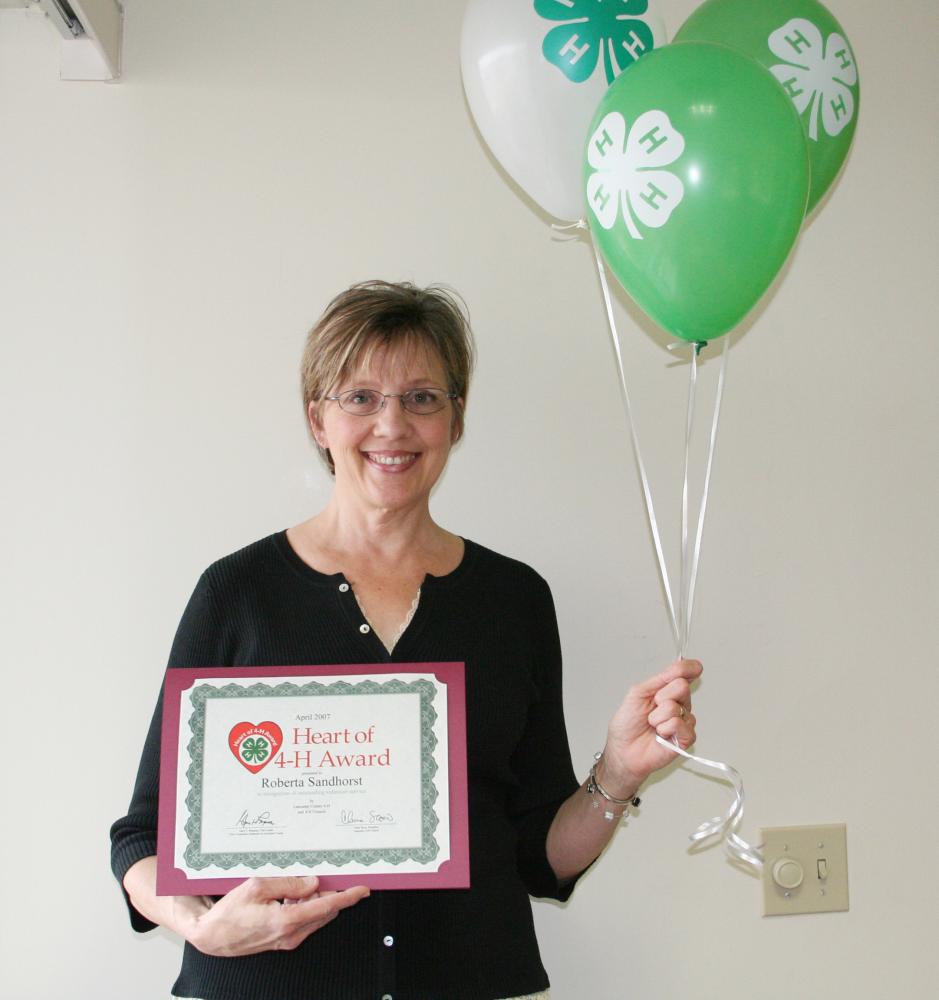 Roberta Sandhorst holding balloons and a certificate