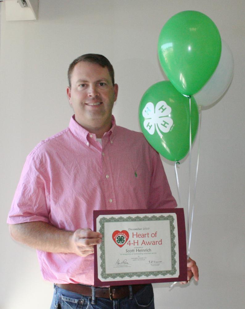 Scott Heinrich holding 4-H balloons and a certificate.
