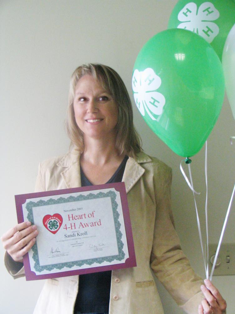 Sandi Kroll holding balloons and a certificate