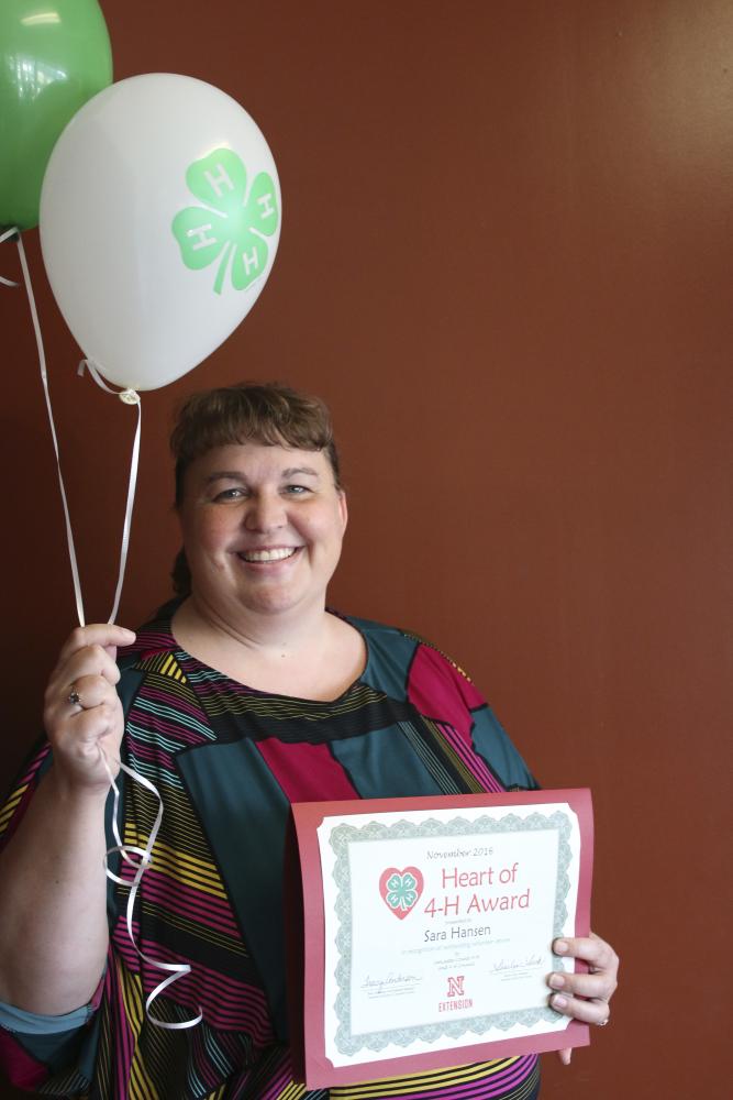 Sara Hansen holding 4-H balloons and a certificate.