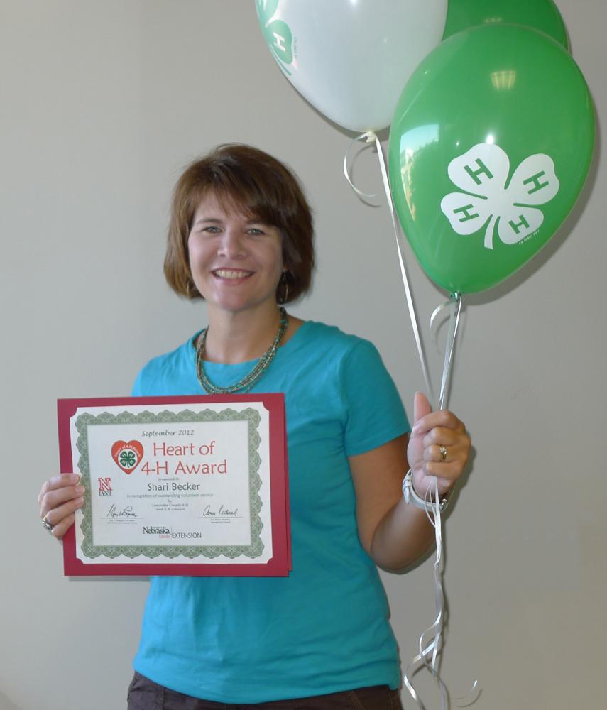 Shari Becker holding 4-H balloons and a certificate.