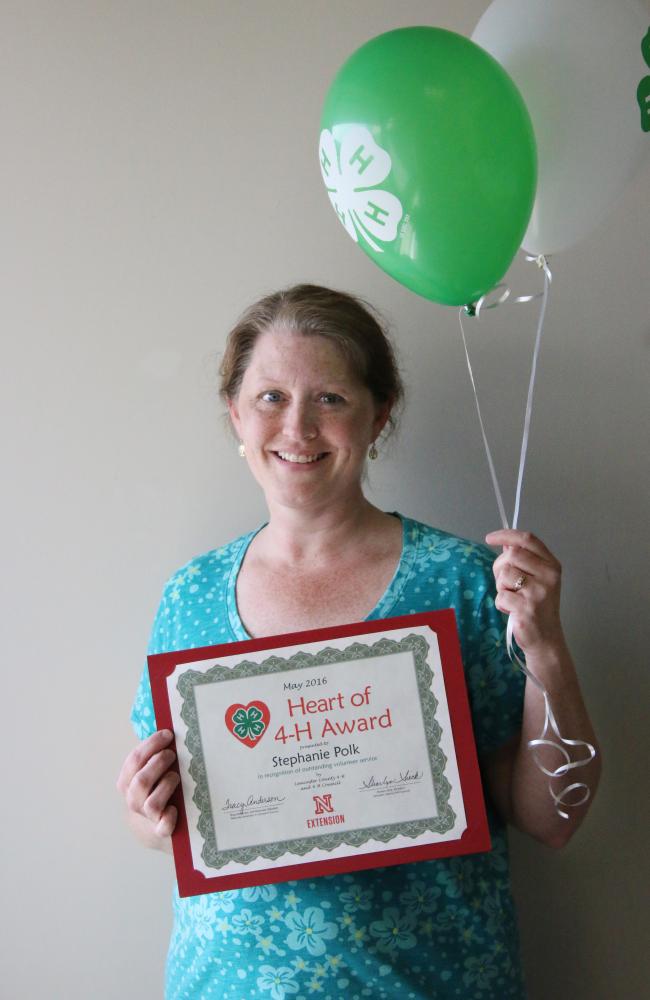Stephanie Polk holding 4-H balloons and a certificate.