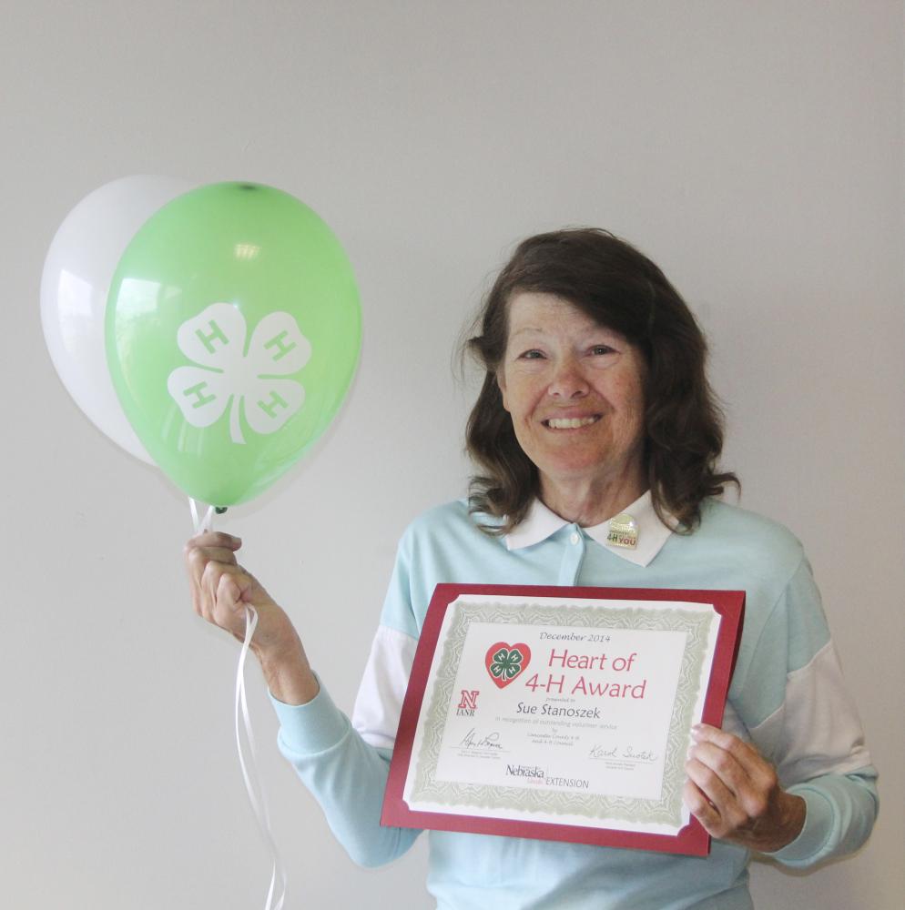 Sue Stanoszek holding 4-H balloons and a certificate.