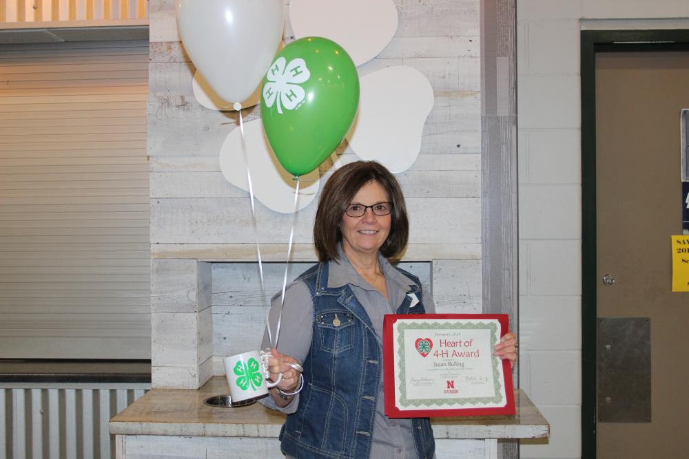 Susan Bulling holding 4-H balloons and a certificate.