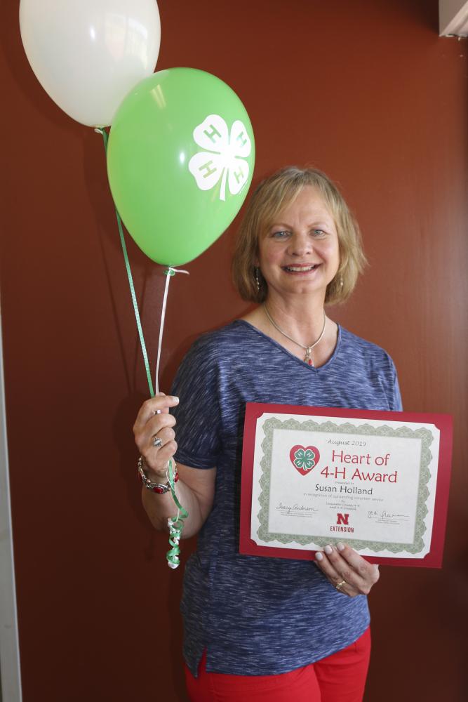 Susan Holland holding 4-H balloons and a certificate.