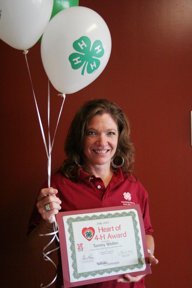 Tammy Wollen holding 4-H balloons and a certificate.