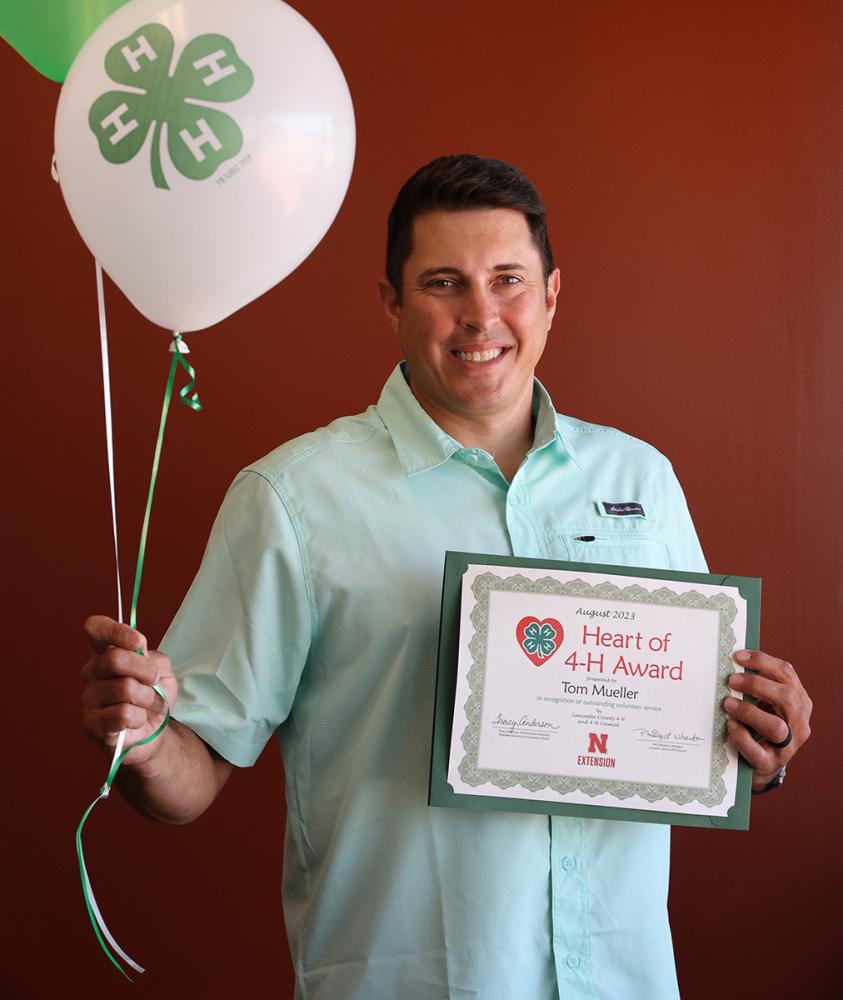 Tom Mueller holding a 4-H certificate and balloons