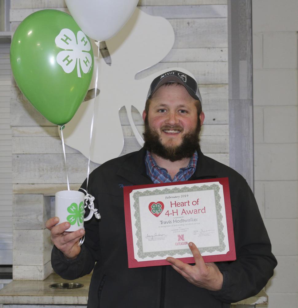 Travis Hodtwalker holding 4-H balloons, a 4-H mug, and a certificate.