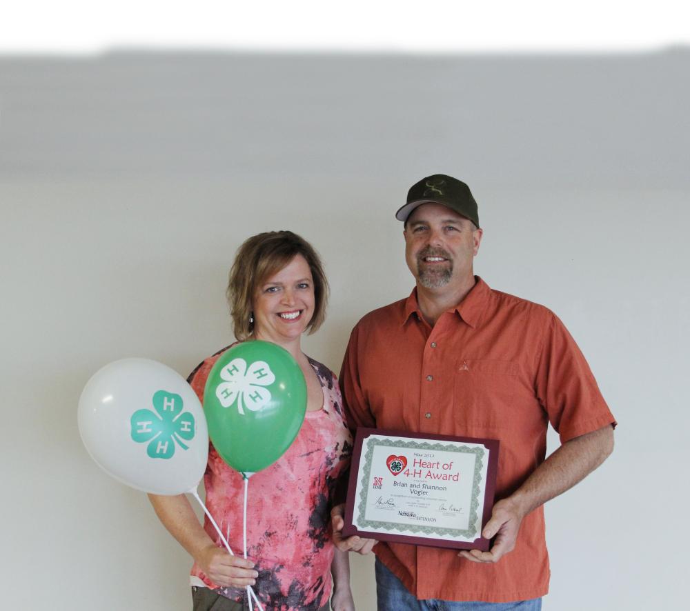 Brian & Shannon Vogler standing together and holding 4-H balloons and a certificate.