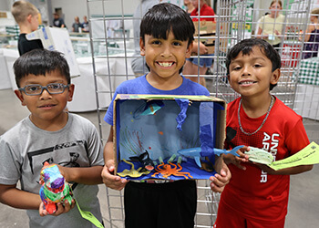 three boys holding items they clearly made or painted