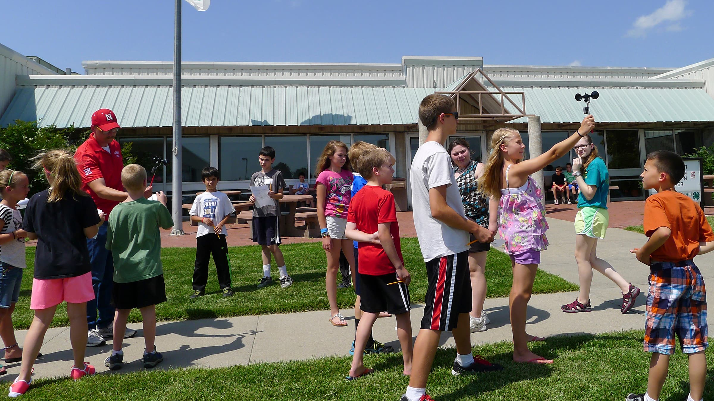 Many youth holding wind measuring devices with an adult helping