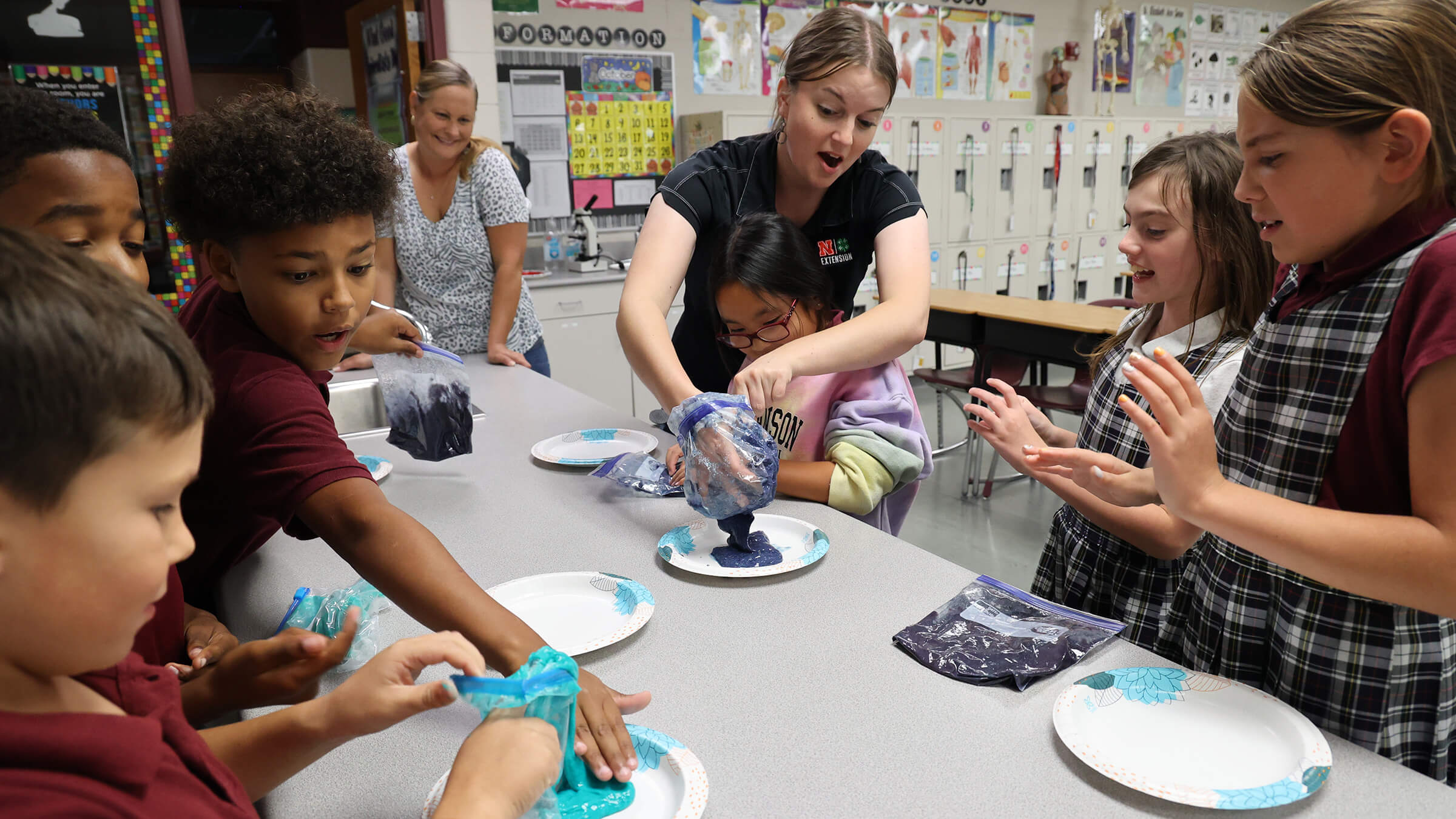 Two women leading several youth in making slime