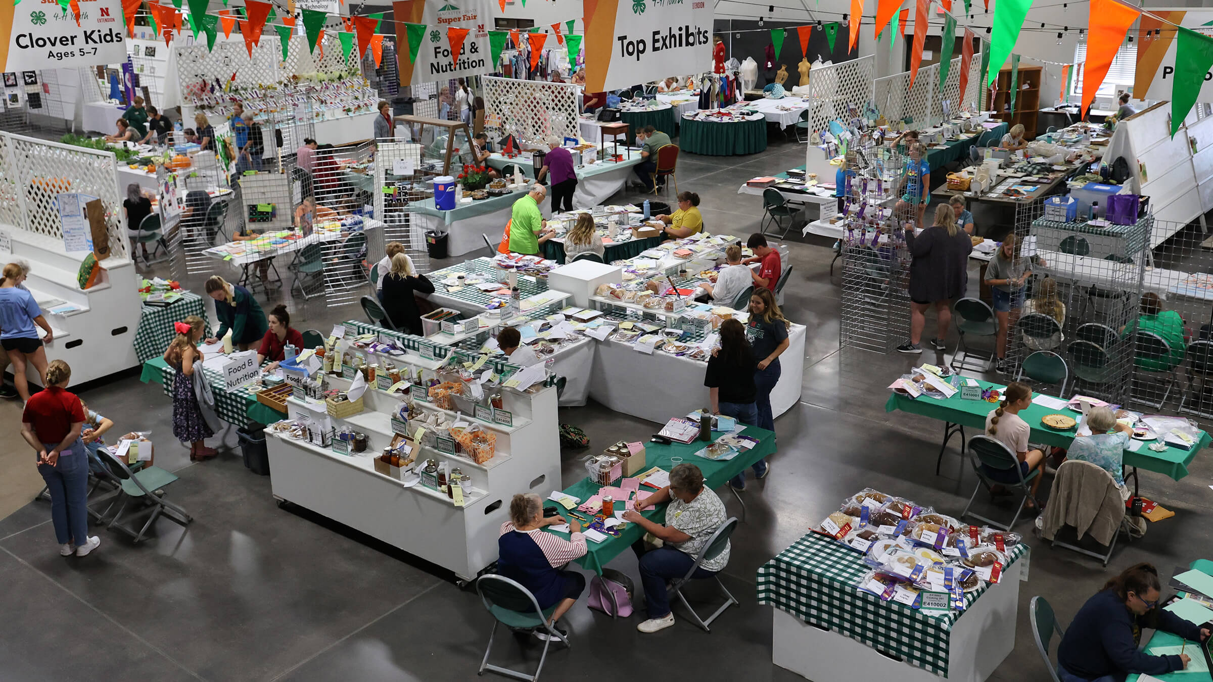 Large room with people among displays full of fair exhibits, including various food items