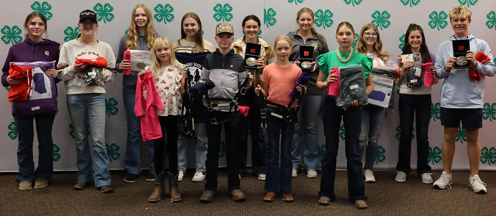 Two rows of youth holding shirts, belt buckles and other swag.