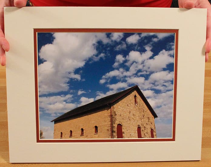Sample front side of an exhibit print of a building with a blue cloudy sky behind it with white may.. Print may be horizontal OR vertical.