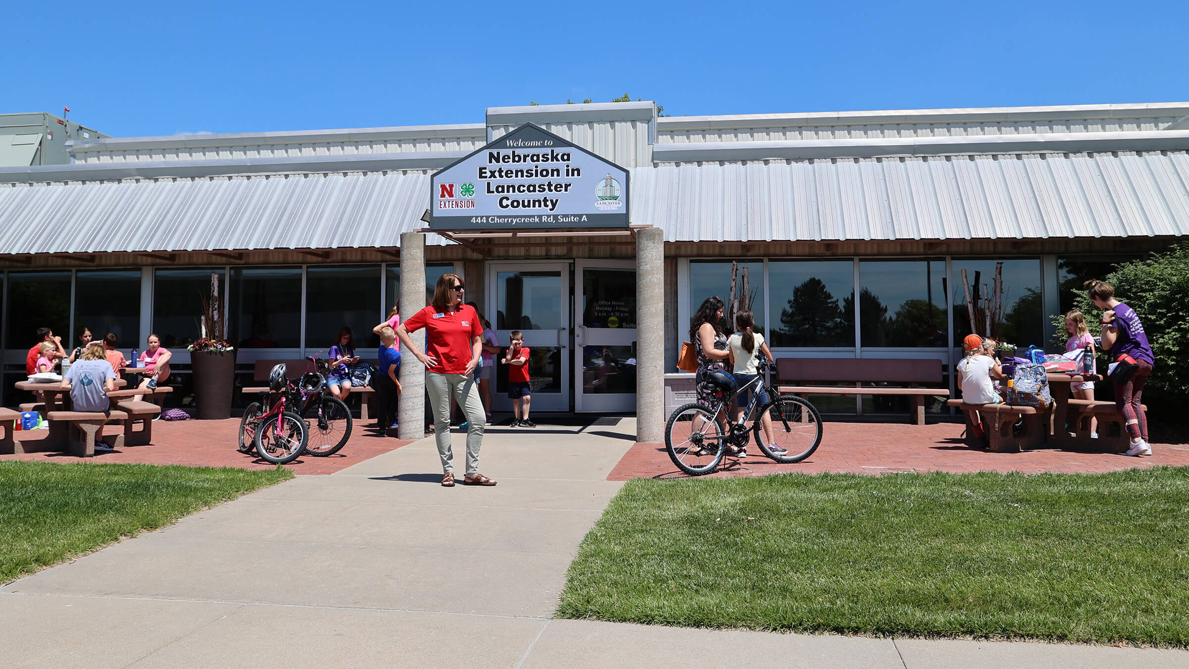 Photo of Tracy Anderson in front of the Nebraska Extension in Lancaster County building with youth during Clover College