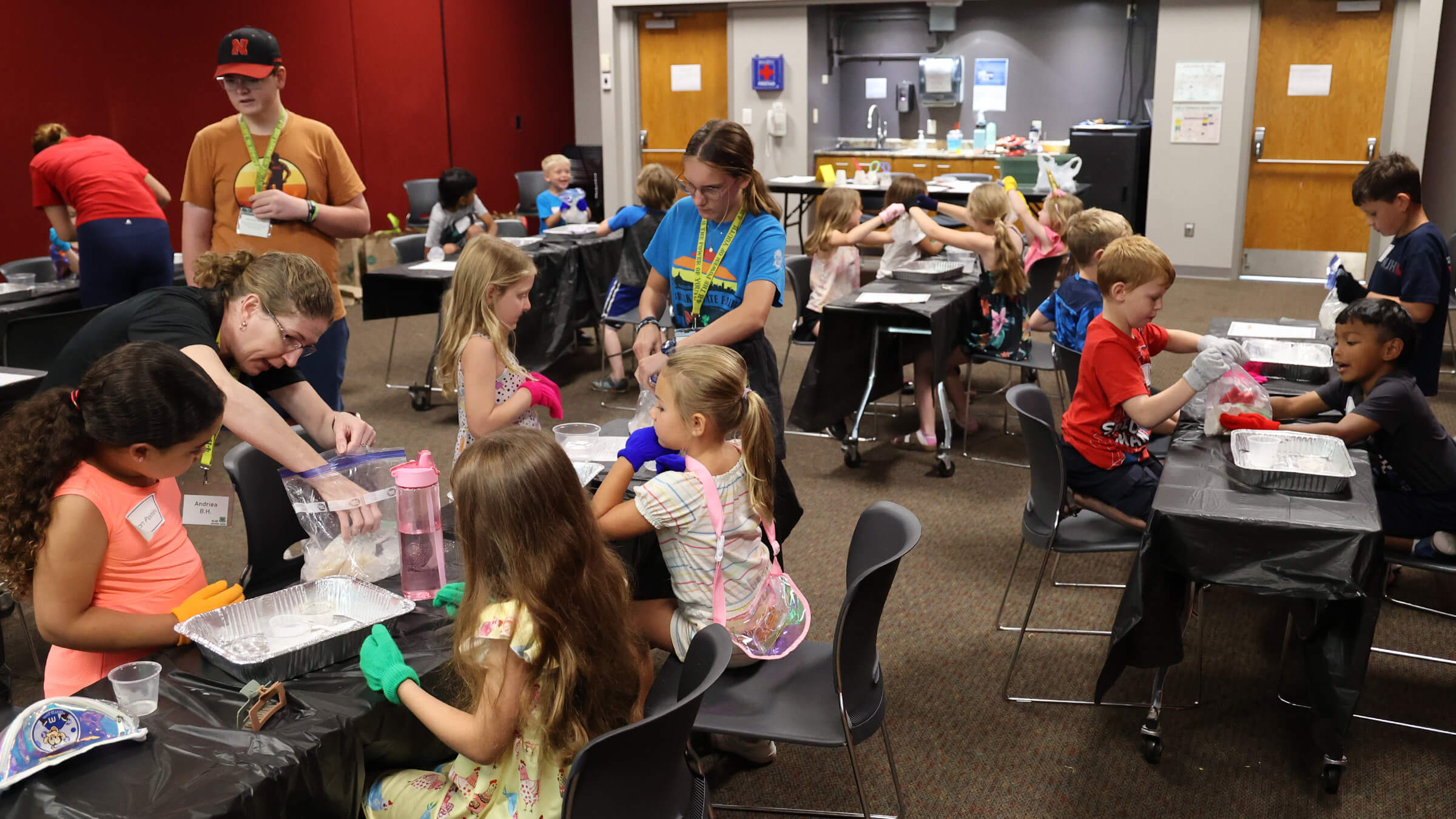 Adults and older teens helping young children make ice cream in bags with ice