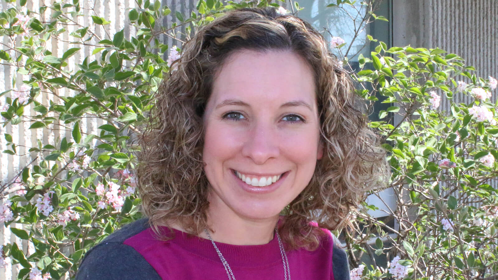 Portrait of Jaci Foged, with a flowering shrub behind her