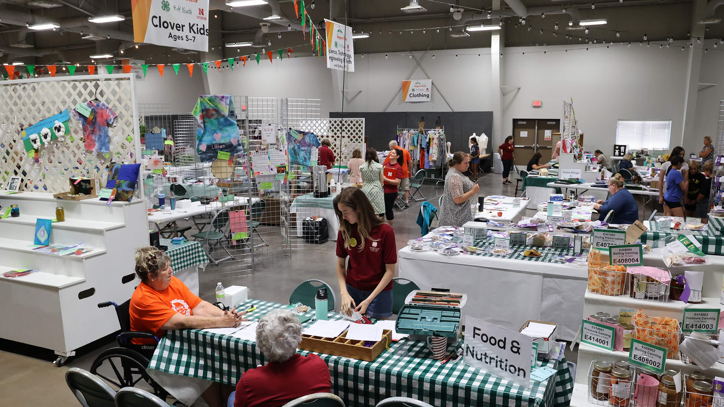 People working among tables and displays full of county fair exhibits