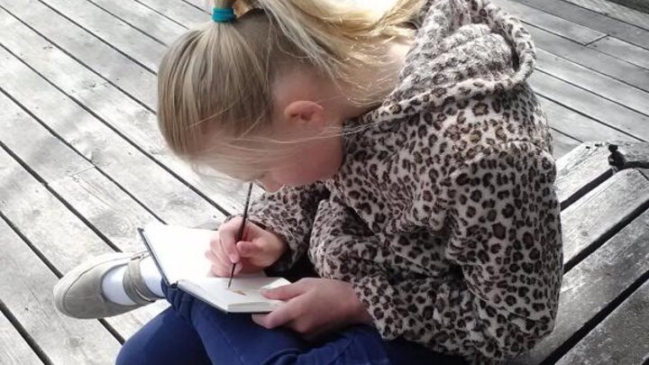 Picture of child writing in a garden journal. 