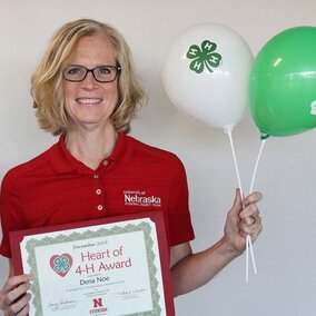 Dena Noe holding a certificate and balloons. 