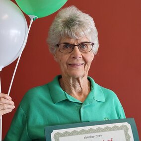 Lorene Bartos holding certificate and balloons 